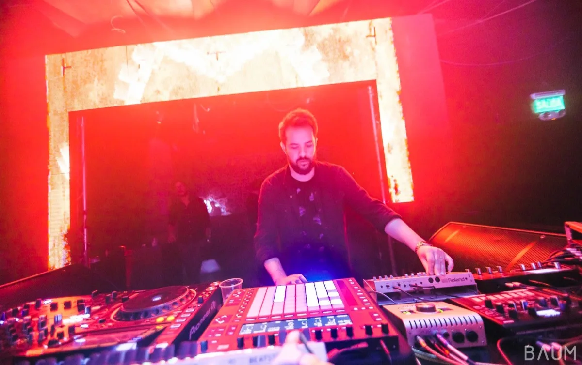 Nowhere Traveler tocando en vivo en Baum, bañado en luz roja, con controlador de pads y sintetizadores